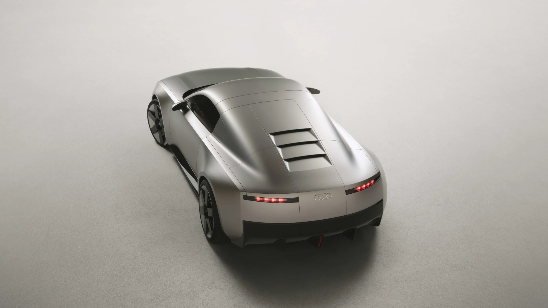 Matte silver Audi concept car with sleek rear design and horizontal taillights on a light gray floor.