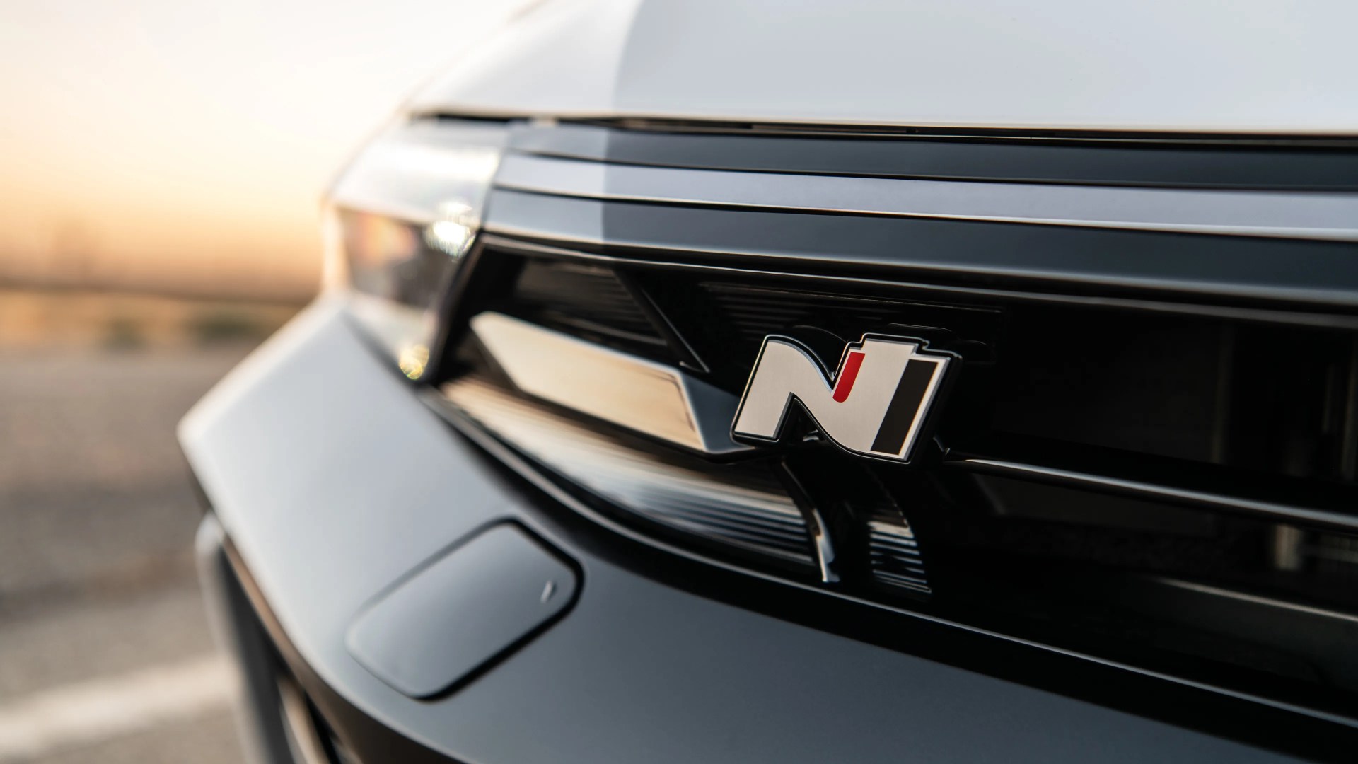 Close-up of a white car front grille with a black and silver "N" emblem and a red accent.