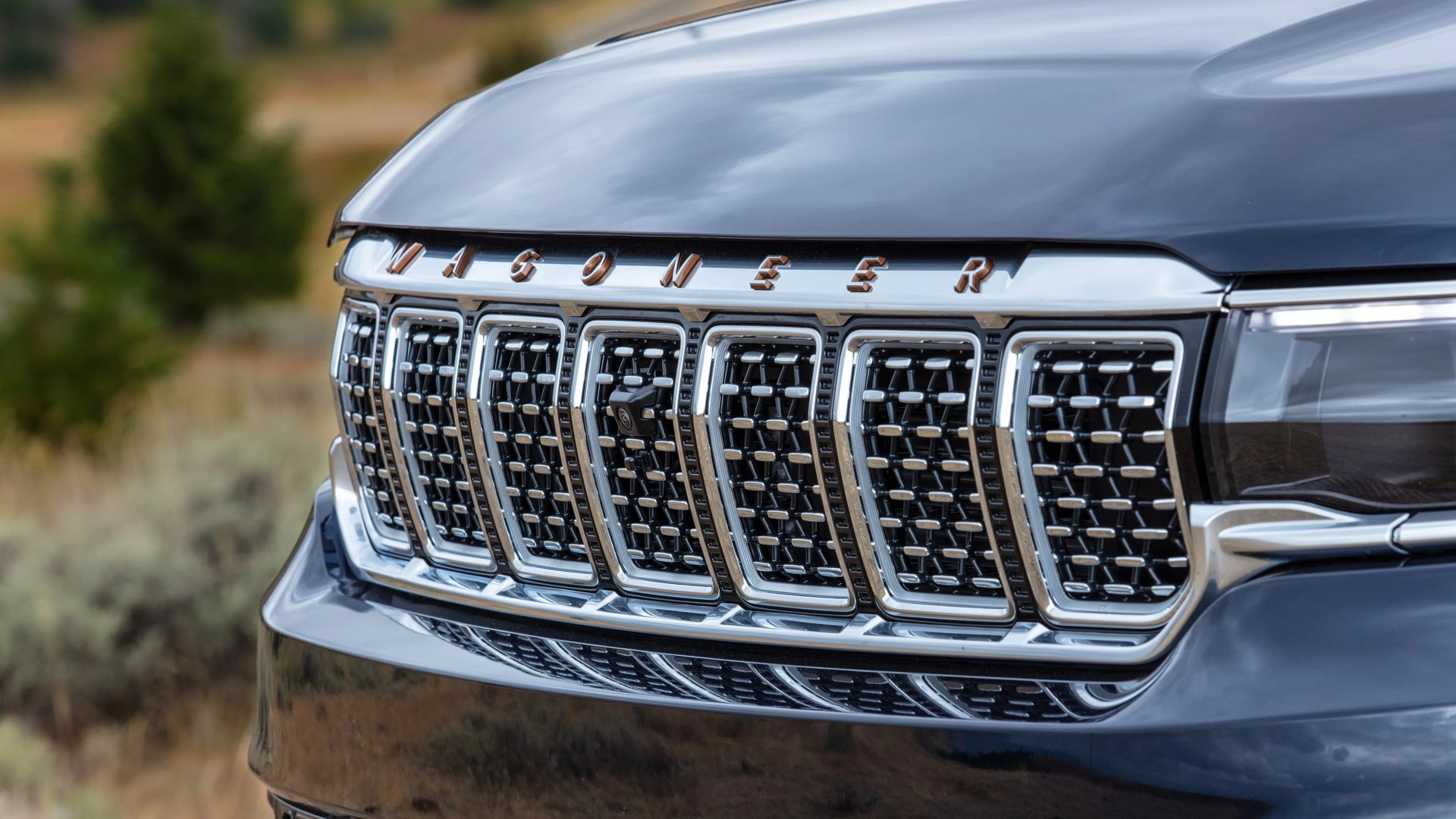 Close-up of a black Jeep Wagoneer front grille with chrome accents and a front camera.