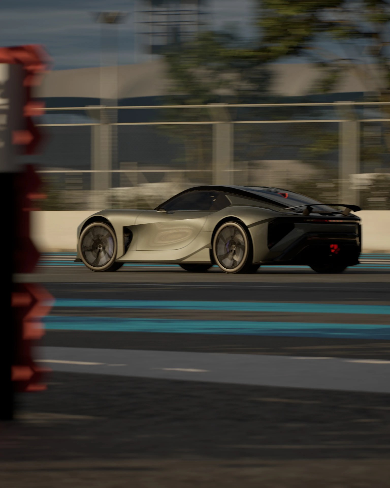Sleek silver sports car with black accents speeding on a racetrack with blue and black markings.