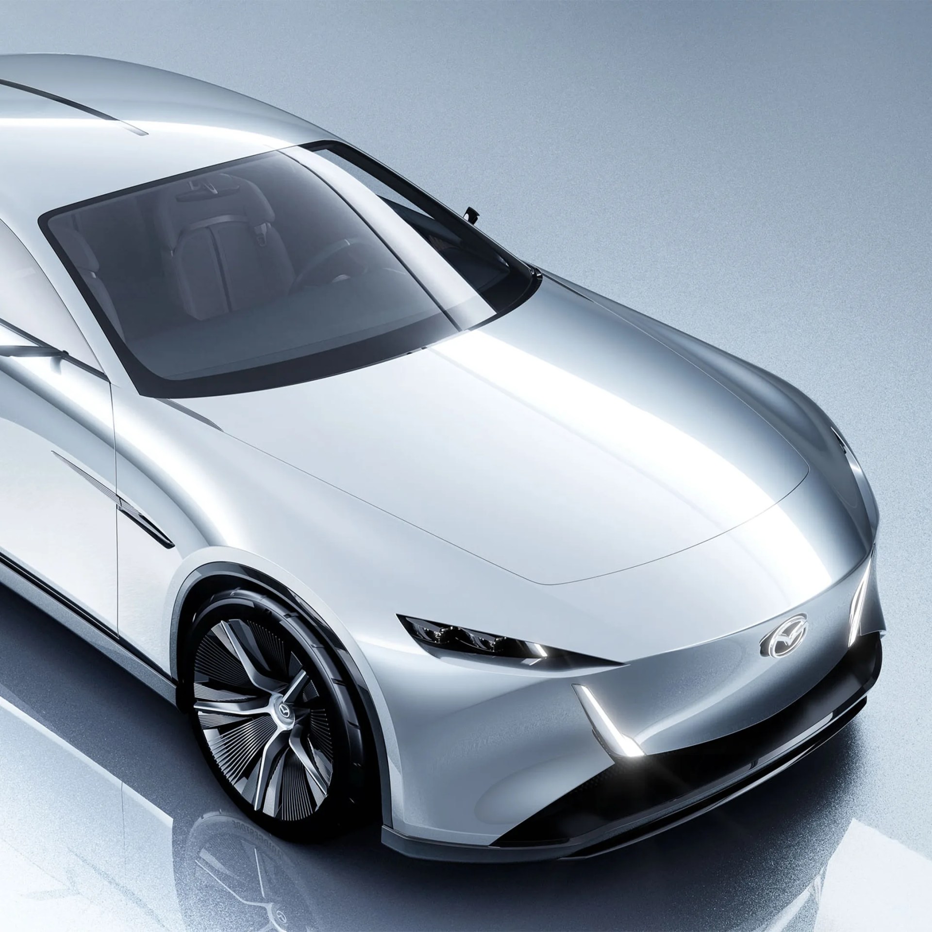 Silver sleek Mazda electric concept car with aerodynamic design and black alloy wheels on reflective surface.