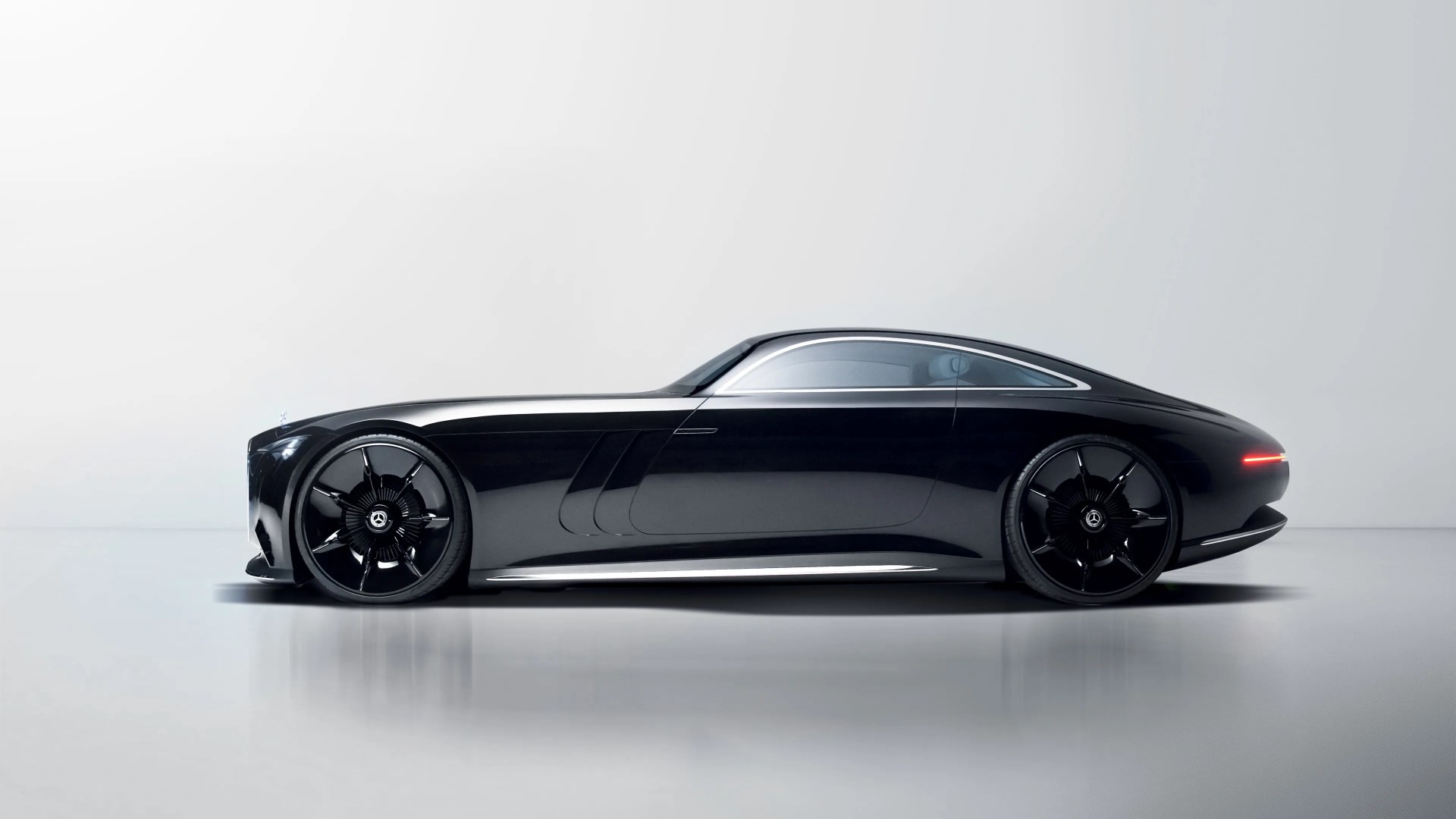 Sleek black luxury coupe with tinted windows and large black alloy wheels on a reflective floor.