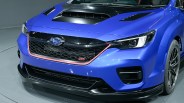 Front view of a blue Subaru STI car with black hood scoop and red trim around the grille.