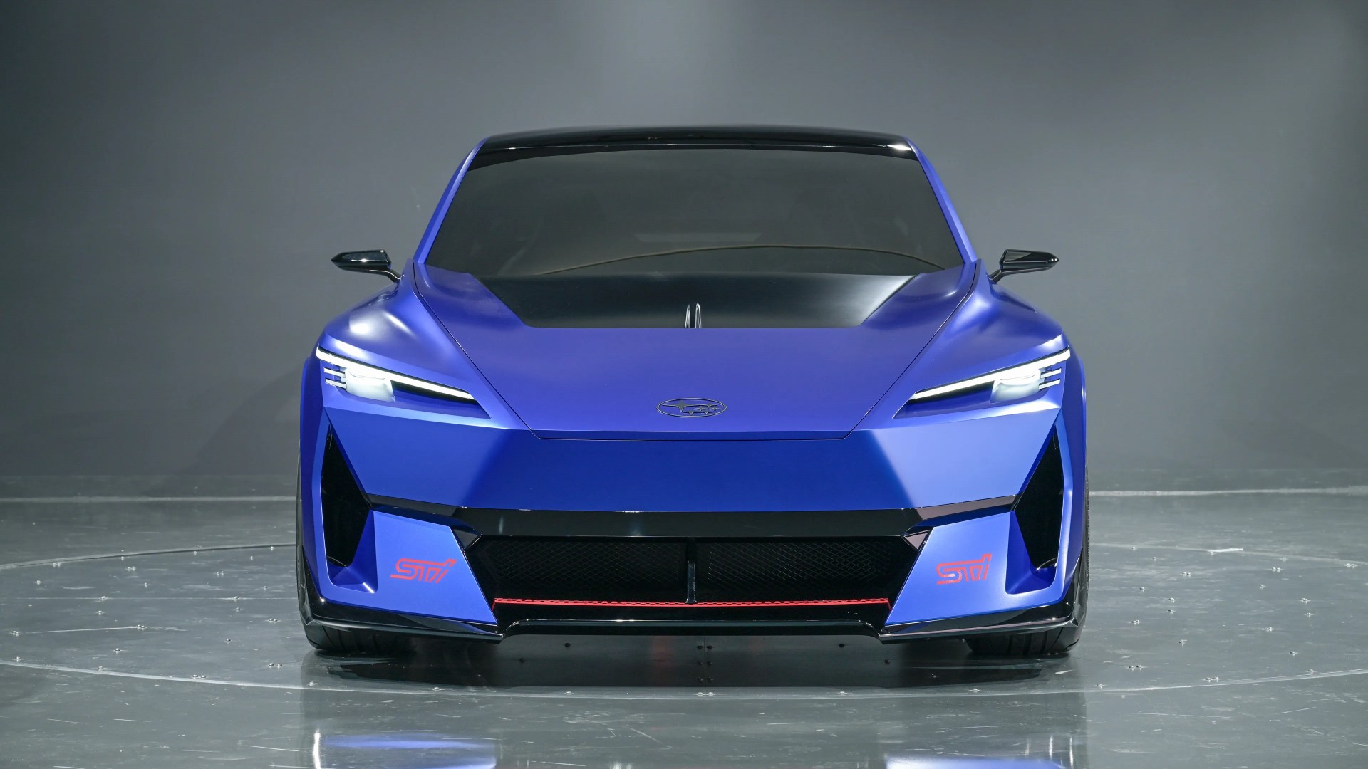 Blue Subaru STI sports car with sleek angular front and black hood in a studio.