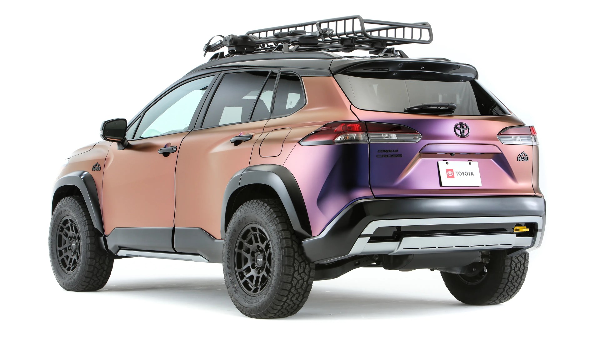 Two-tone matte bronze and purple Toyota Corolla Cross SUV with black roof rack and off-road tires on a white background.