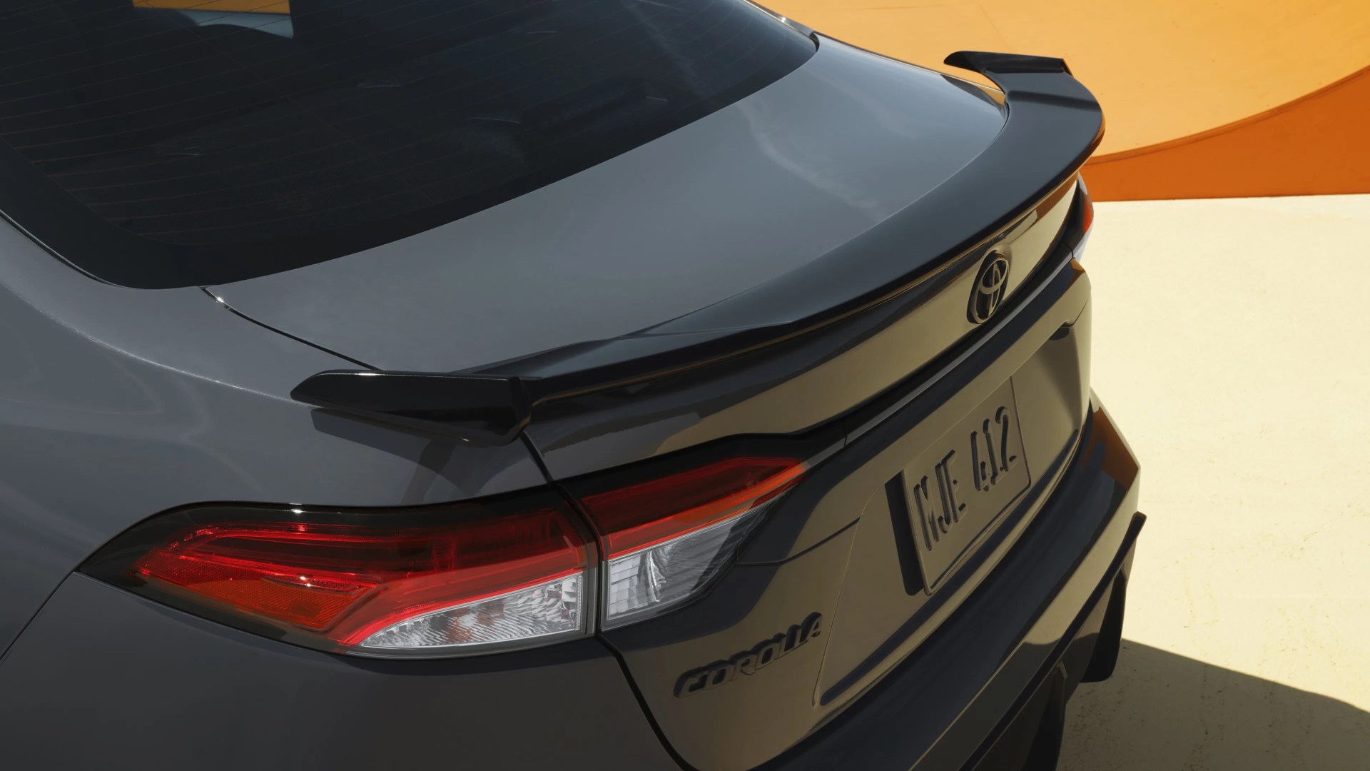 Rear view of a gray Toyota Corolla with a black spoiler and red taillights.
