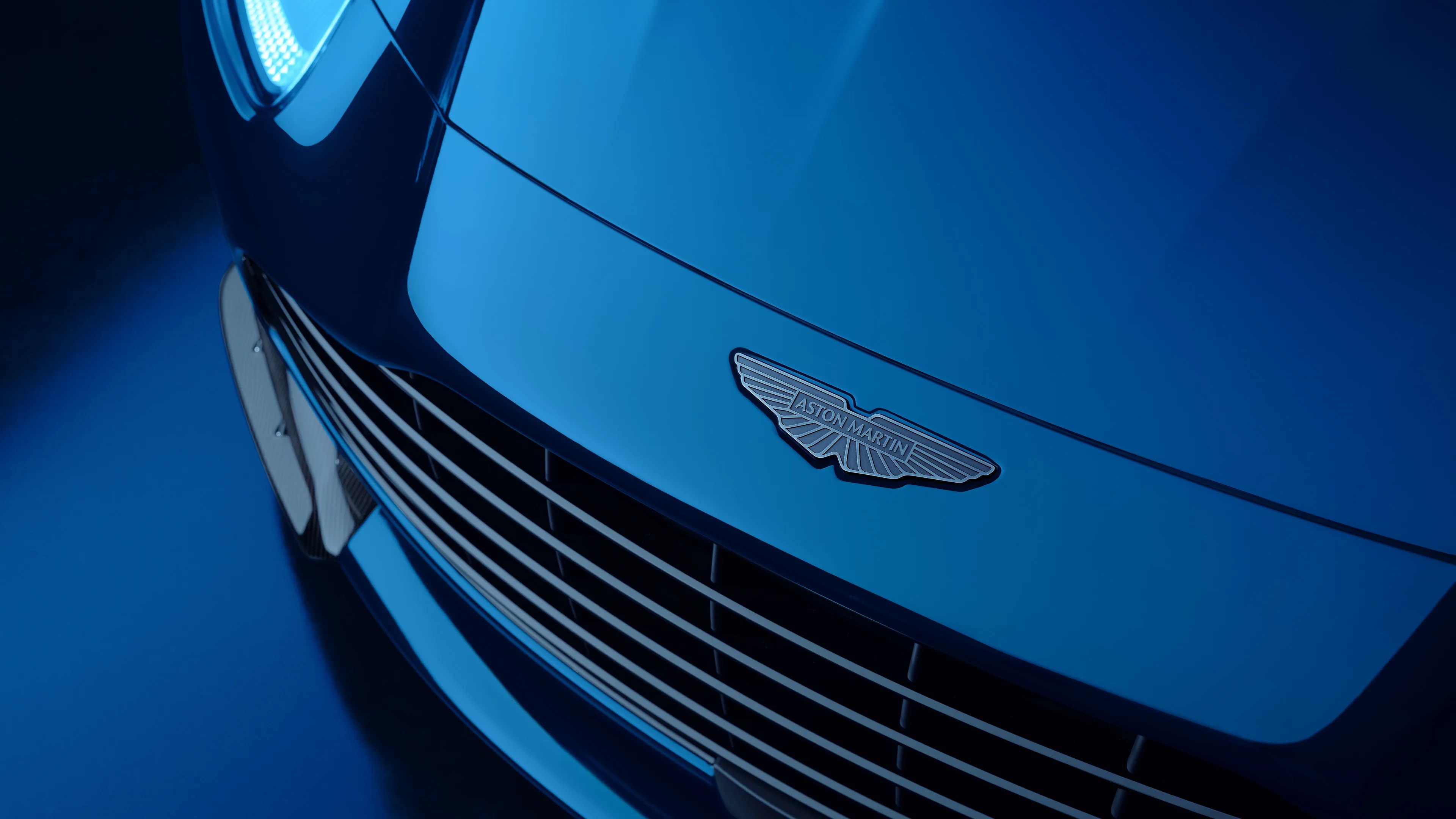 Front grille and hood of a blue Aston Martin car with the logo visible.