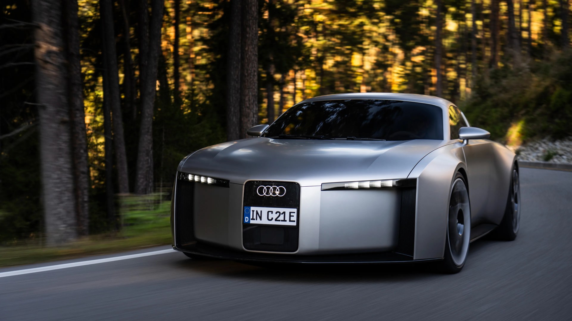 Silver Audi electric concept car with futuristic design driving on a forest road.