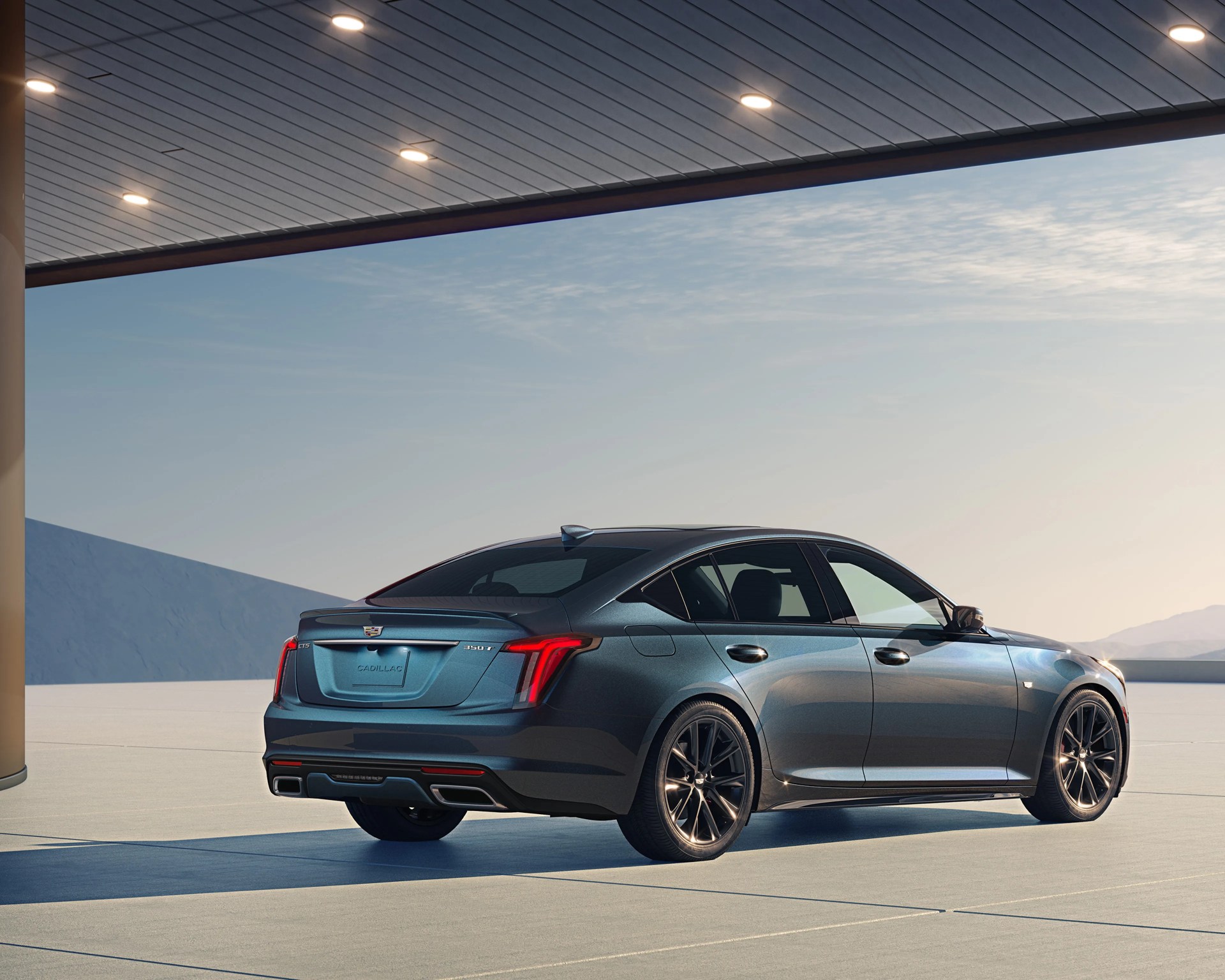 Dark gray Cadillac CT5 sedan parked under a modern canopy with illuminated ceiling lights.