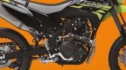 Close-up of the black and green Kawasaki KLX 230 SM motorcycle engine and frame against an orange background.