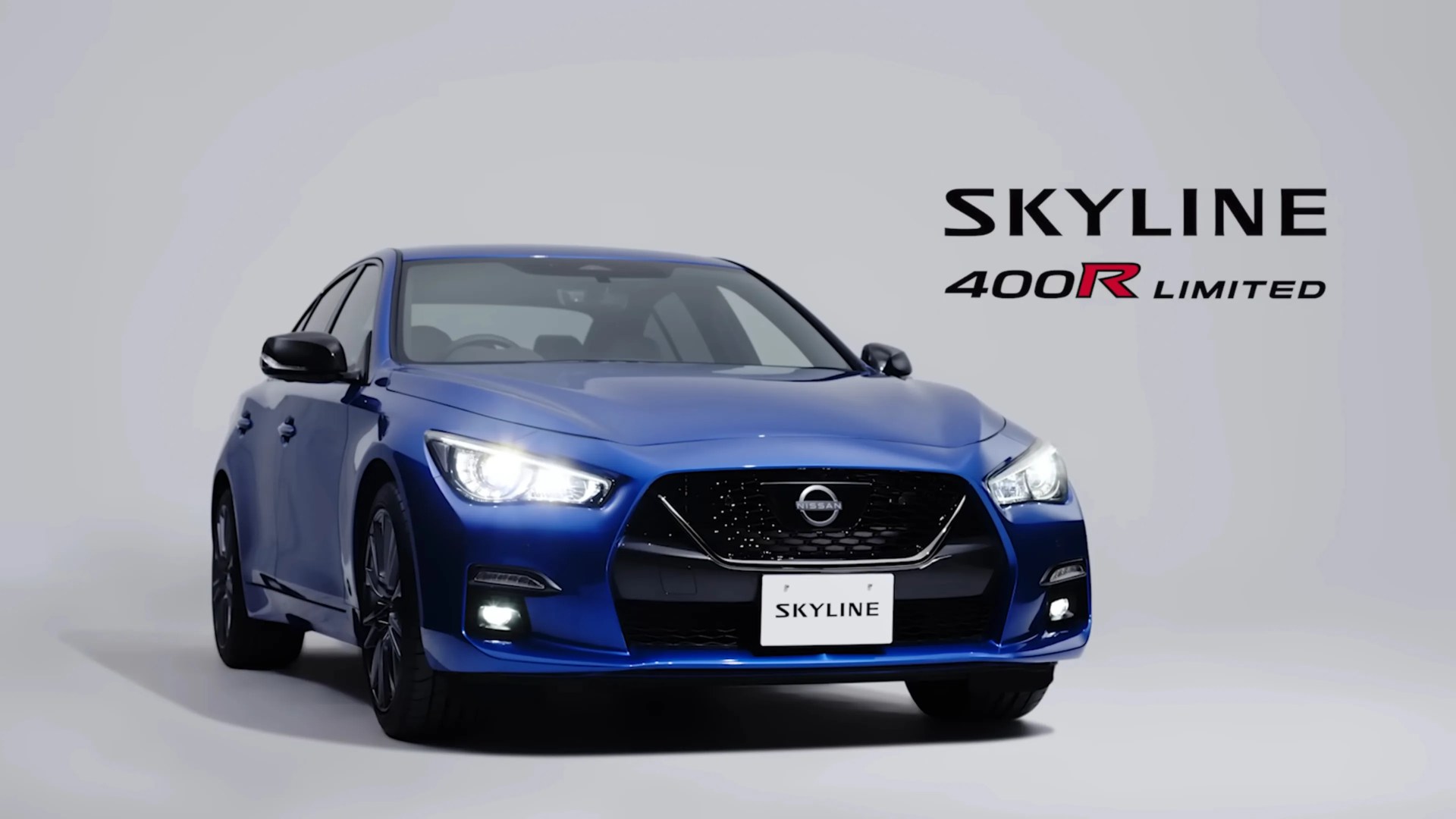 Blue Nissan Skyline 400R Limited sedan with headlights on against a plain background.