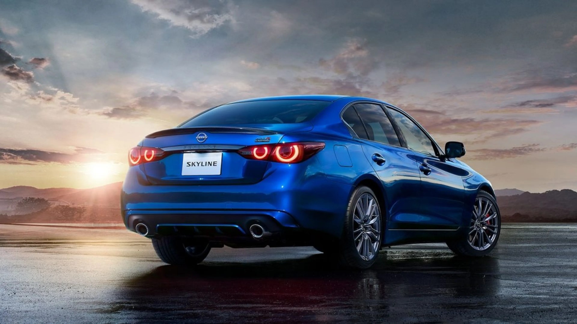 Blue Nissan Skyline sedan with illuminated rear taillights parked on wet pavement at sunset.