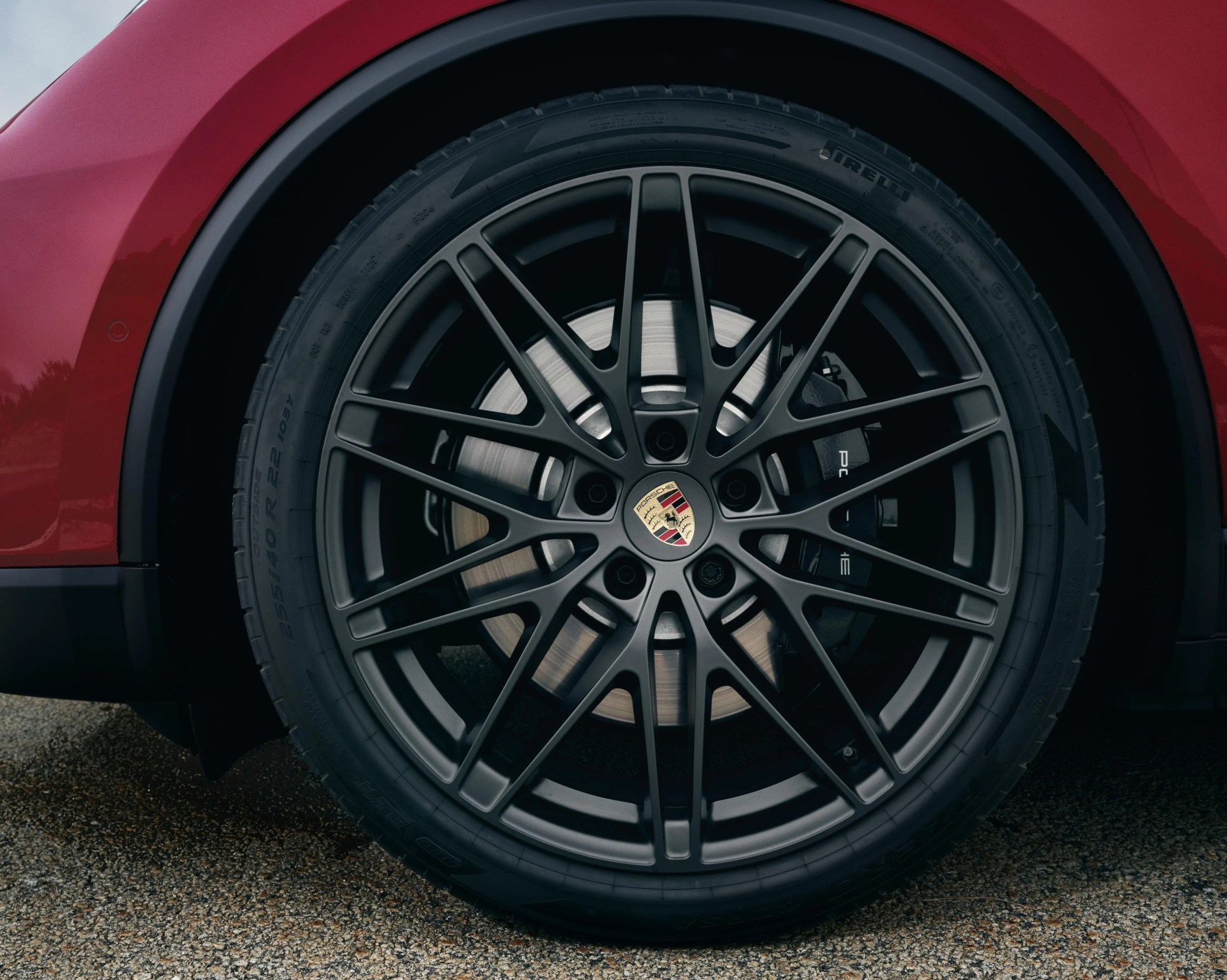 Close-up of a black multi-spoke Porsche wheel with Pirelli tire on a red car.