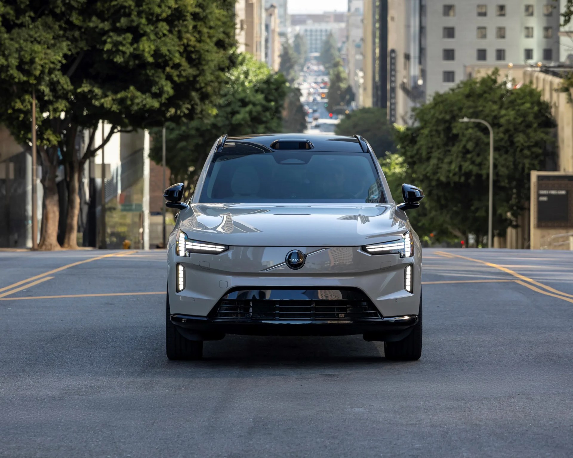 Front view of a silver Volvo SUV with LED headlights on a city street.