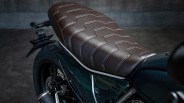 Brown leather motorcycle seat with zigzag stitching on a dark green bike frame.