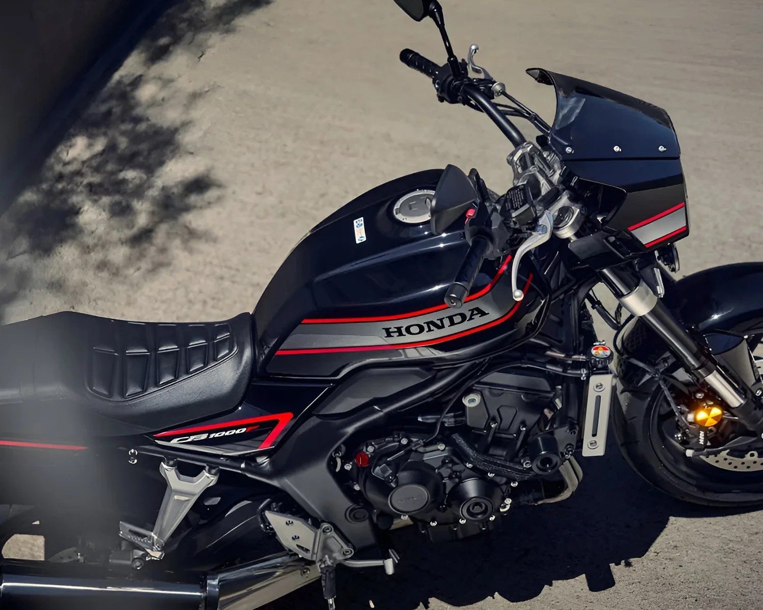 Black Honda CB1000 motorcycle with red and silver stripes parked on a paved surface.