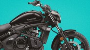 Black Kawasaki motorcycle with visible engine and front wheel against a turquoise background.