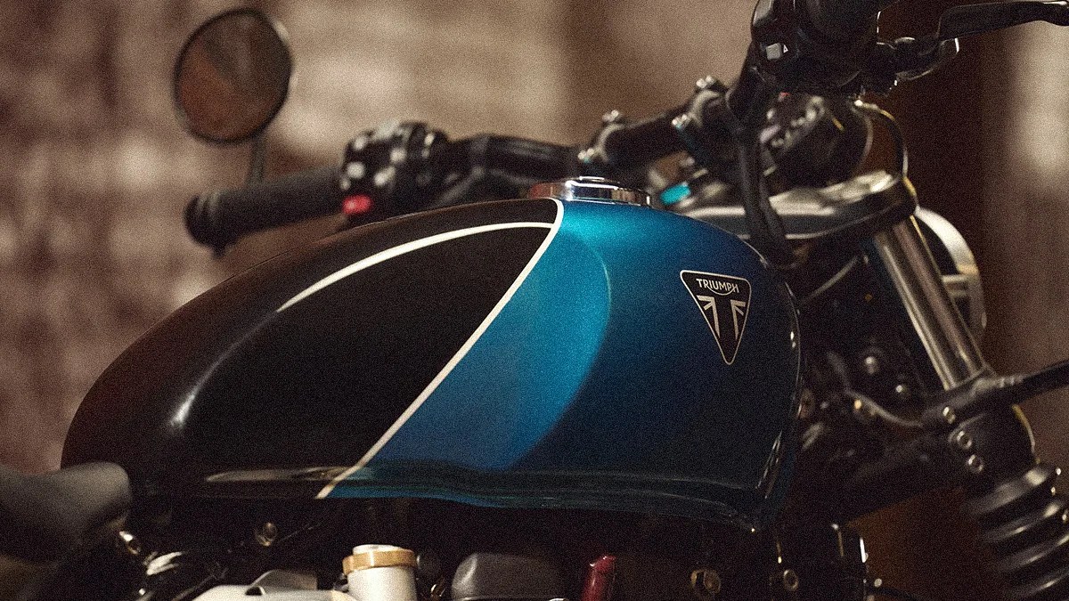 Blue and black Triumph motorcycle fuel tank with white pinstripe and chrome fuel cap.