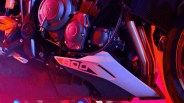 Close-up of a motorcycle engine with a white and black fairing piece labeled "800" under colorful red and purple lighting.