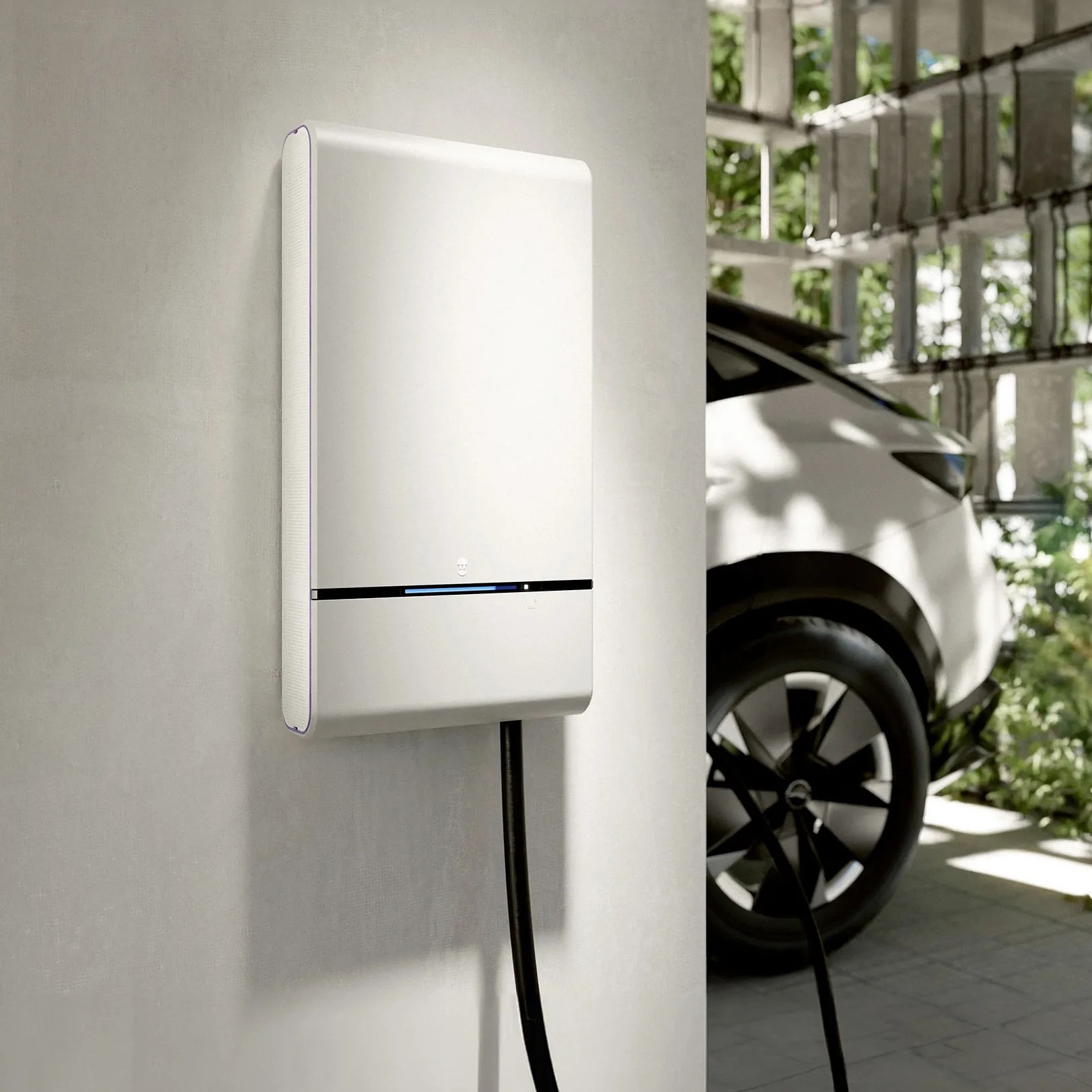 White electric vehicle charging station mounted on a wall with a black cable connected to a white car.