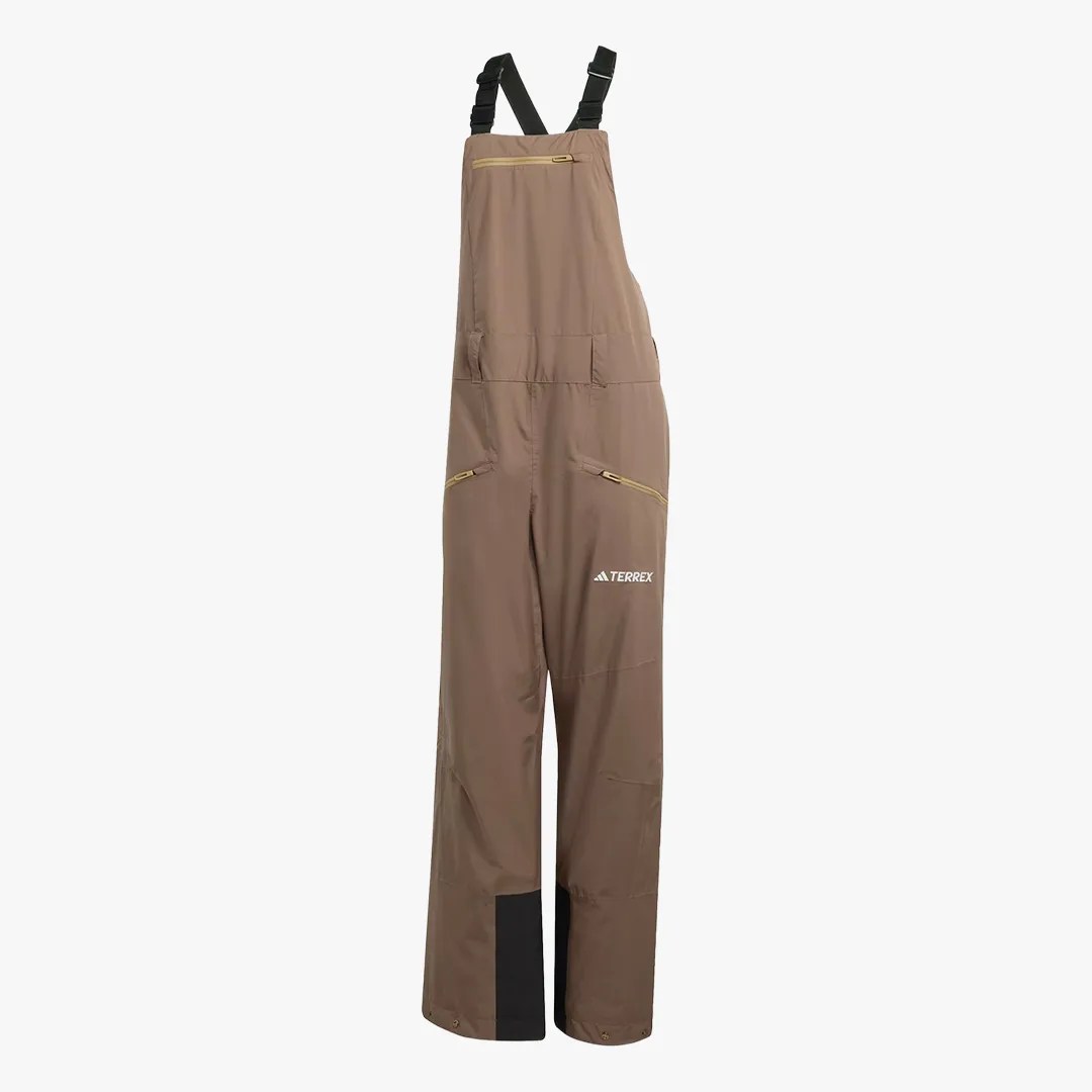 Brown outdoor bib pants with black adjustable shoulder straps and zippered pockets, featuring a white Terrex logo.