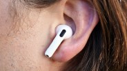 White wireless earbud inserted in a person's ear with brown hair visible.