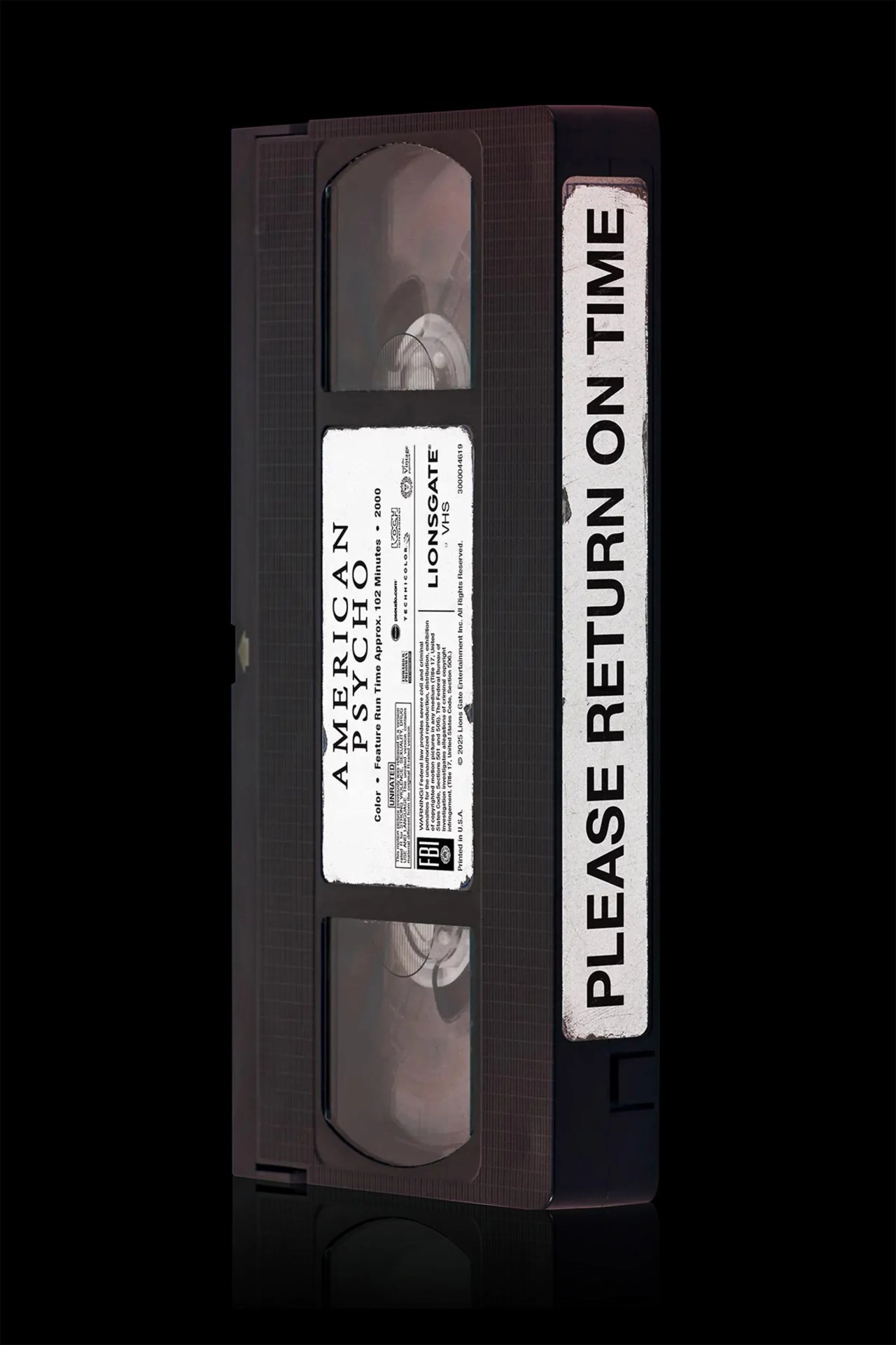 Black VHS tape labeled "American Psycho" with a white sticker reading "Please Return On Time" on the side.