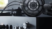 Black Audio-Technica open-back headphones connected to a silver audio amplifier with knobs.