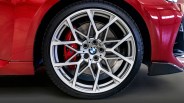 Silver multi-spoke BMW alloy wheel with red brake caliper on a red car.