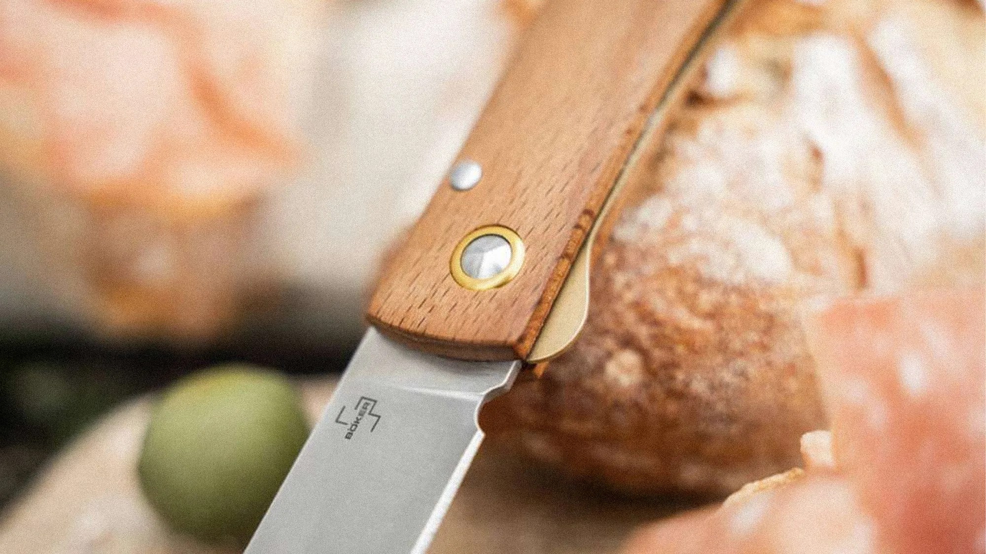 Close-up of a folding knife with a wooden handle and a stainless steel blade resting on a surface.