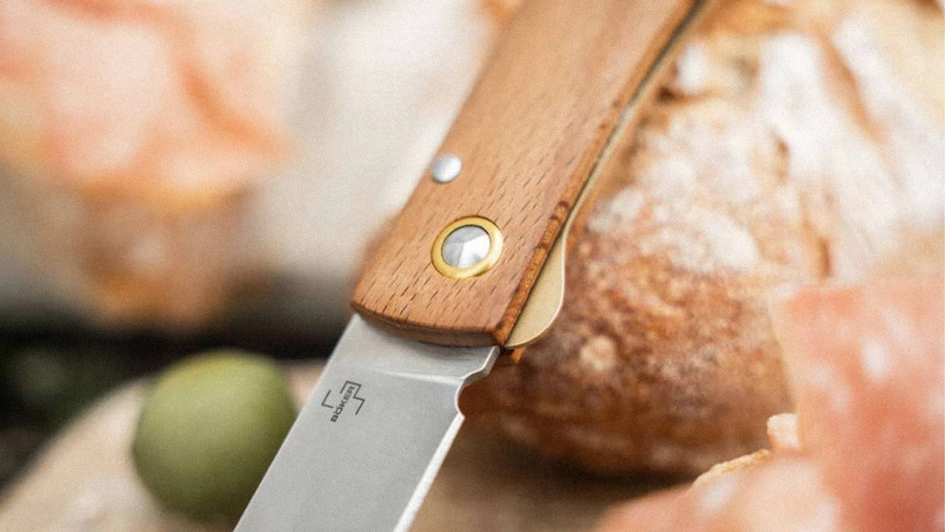 Close-up of a folding knife with a wooden handle and a stainless steel blade resting on a surface.