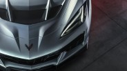 Front view of a silver Chevrolet Corvette with sharp headlights and black mesh grille on a concrete floor.