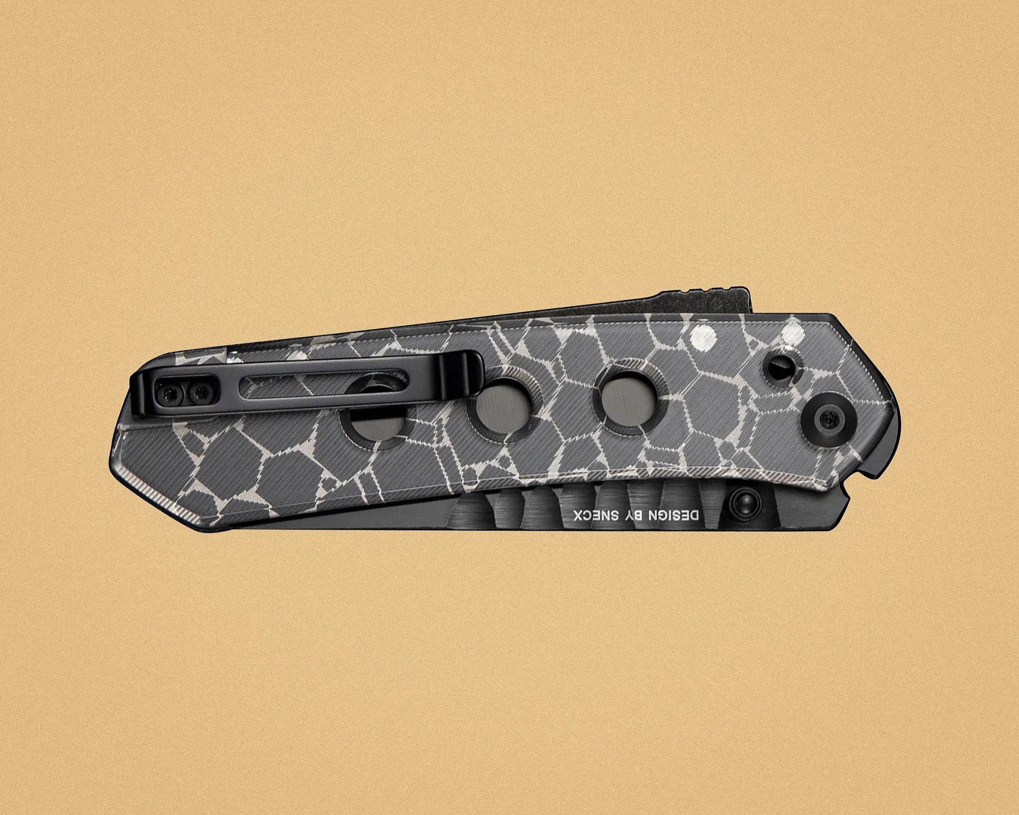 Folded pocket knife with a gray and white cracked pattern handle and black clip on a beige background.