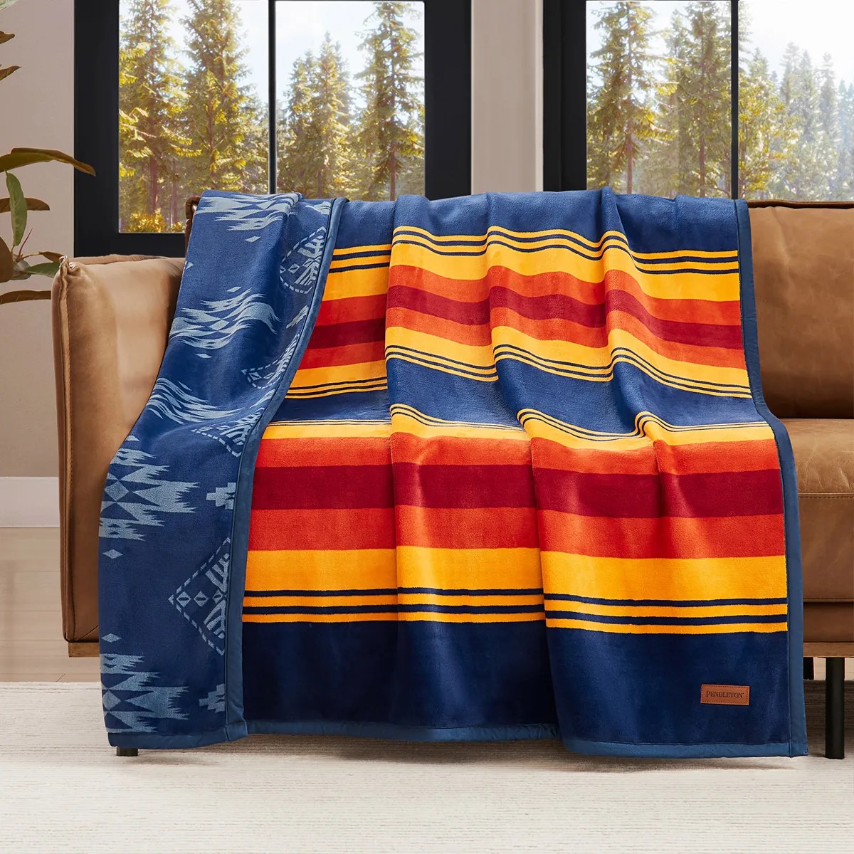 Blue, orange, red, and yellow striped blanket with geometric patterns draped over a tan sofa.