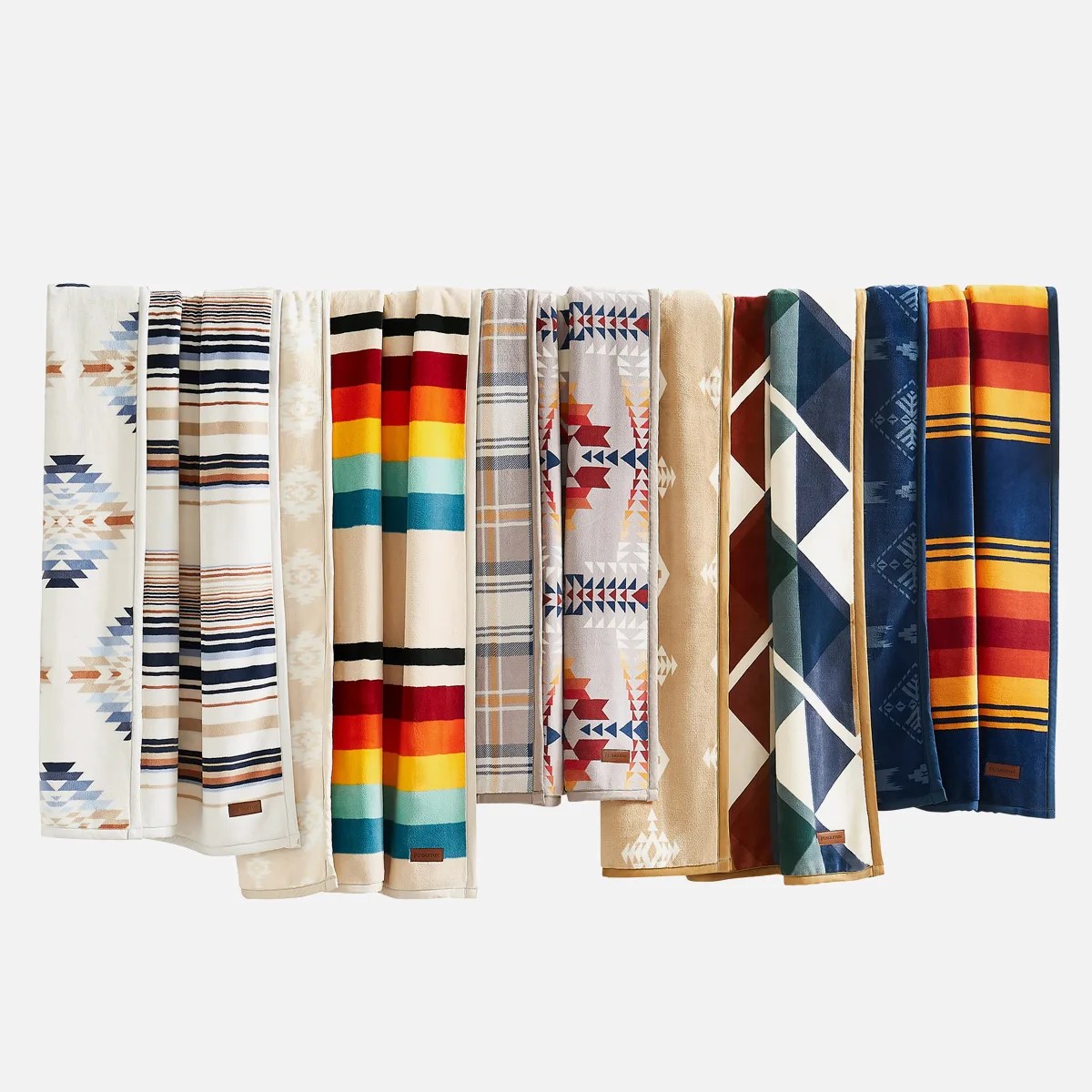 Ten folded blankets with various colorful geometric and striped patterns arranged side by side.