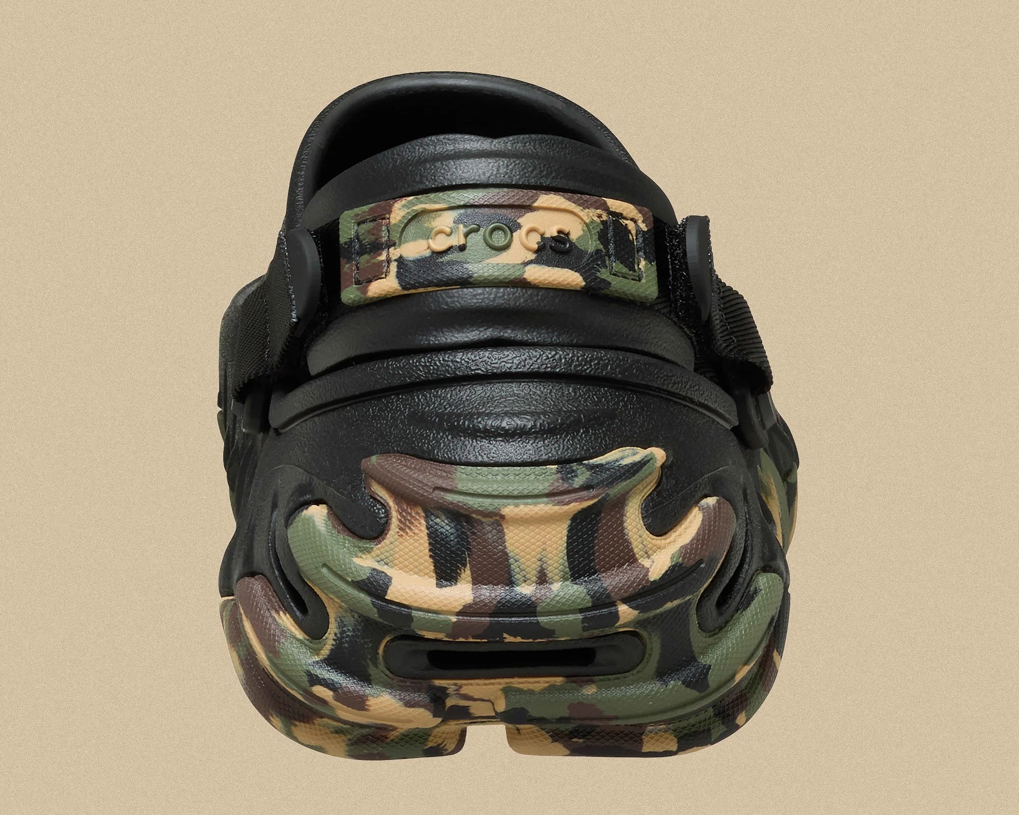 Rear view of a black Crocs clog with green, brown, and tan camouflage accents on the heel and strap.