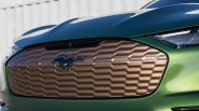 Front grille of a green Ford Mustang Mach-E with a bronze honeycomb pattern and Mustang logo.