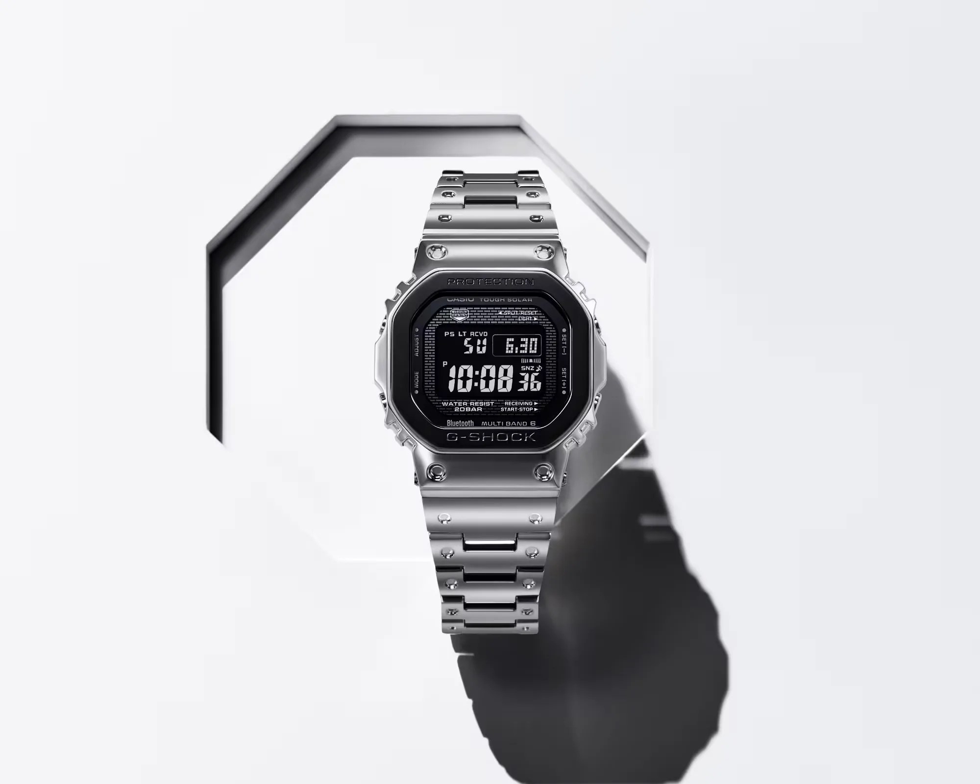 Silver stainless steel Casio G-Shock digital watch with black face and metal link band on white geometric background.