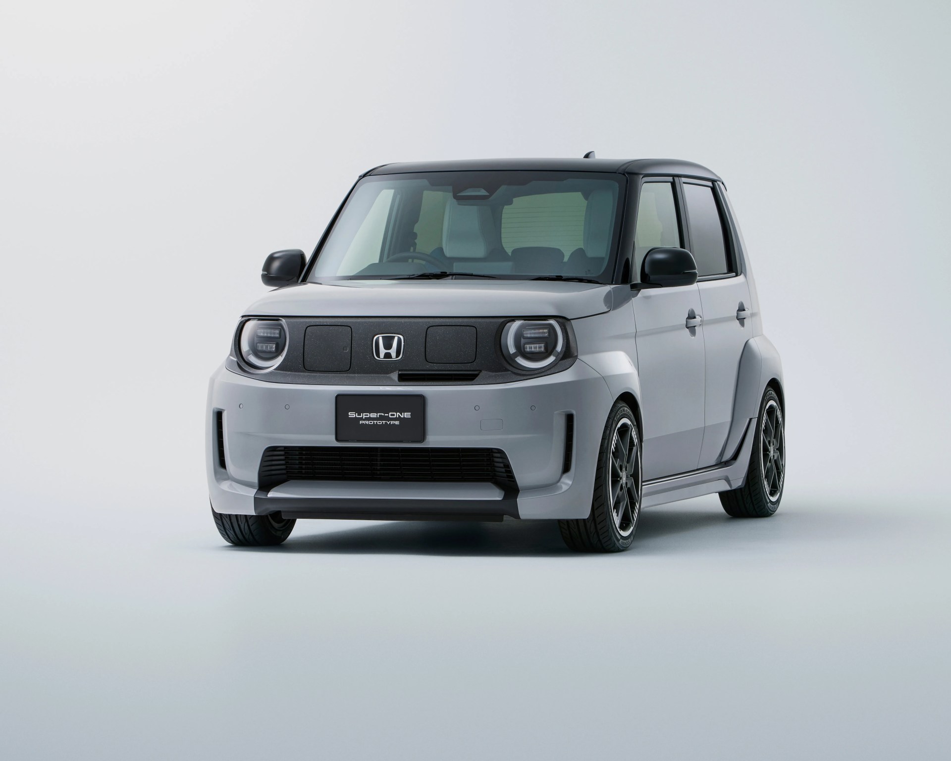 Compact silver Honda Super-ONE prototype car with black roof and sporty wheels on a plain background.