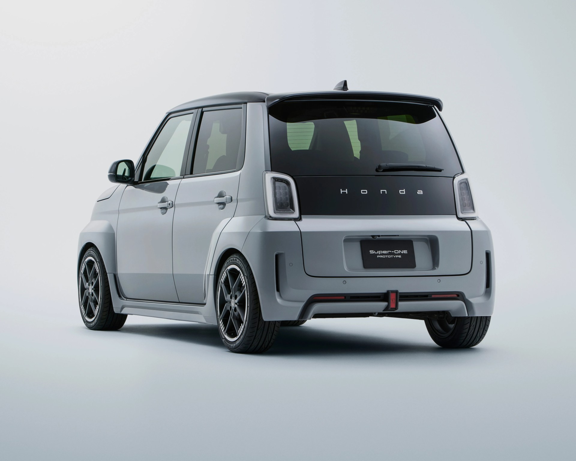 Compact silver Honda Super-ONE prototype car with black roof and tinted rear windows, shown from rear side.