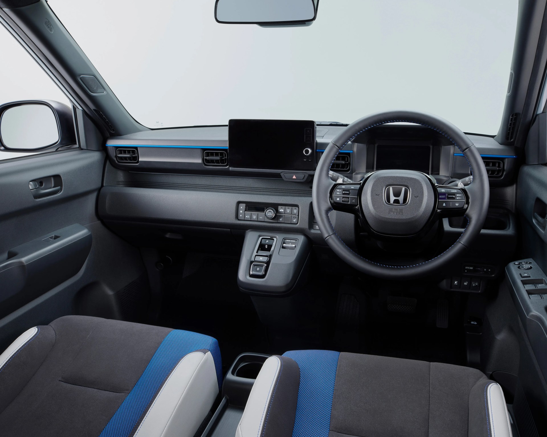 Interior of a Honda car featuring a black and blue fabric seats, digital dashboard, and touchscreen display above the center console.