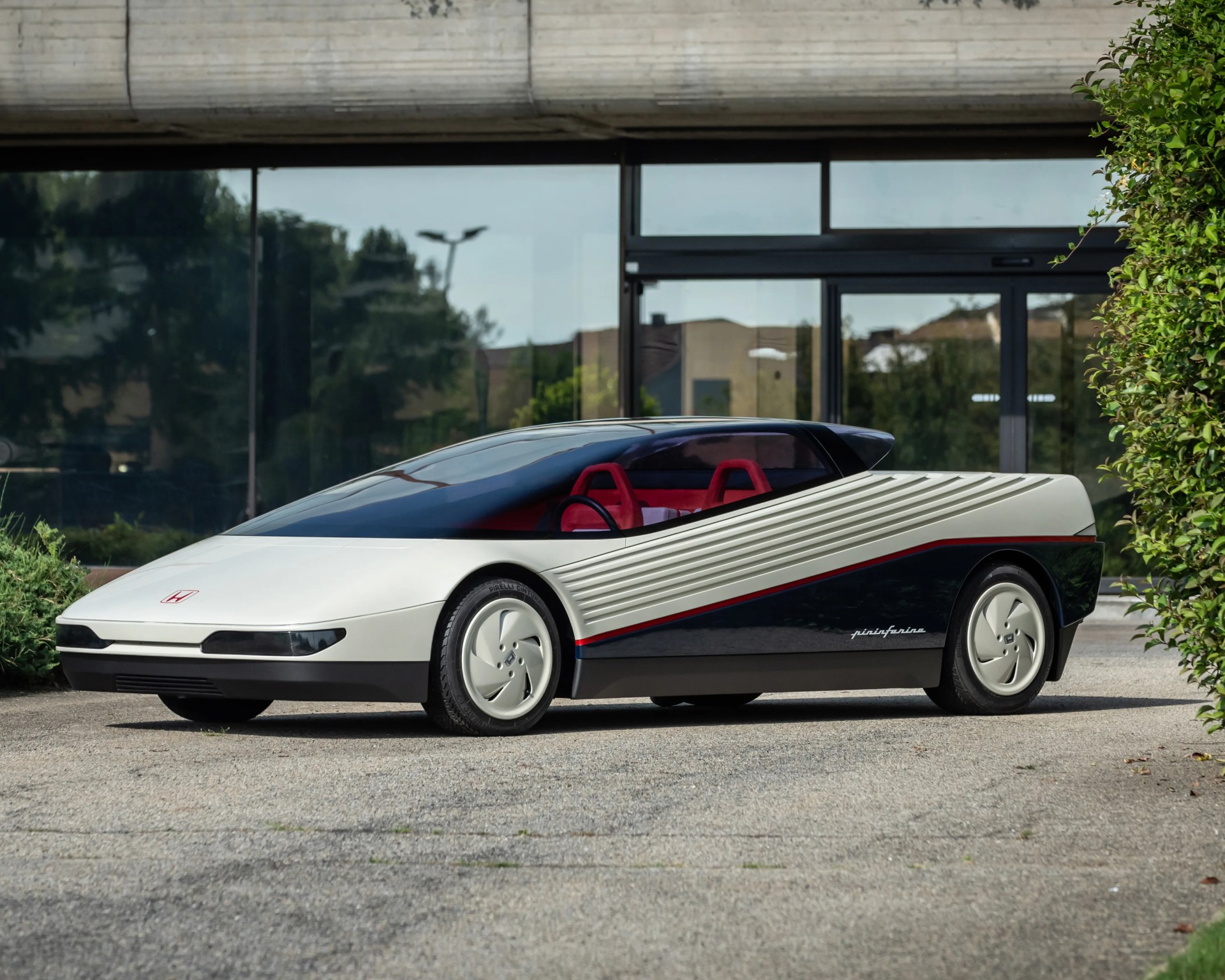 White and black futuristic concept car with red interior and Pininfarina logo on the side, parked on pavement.