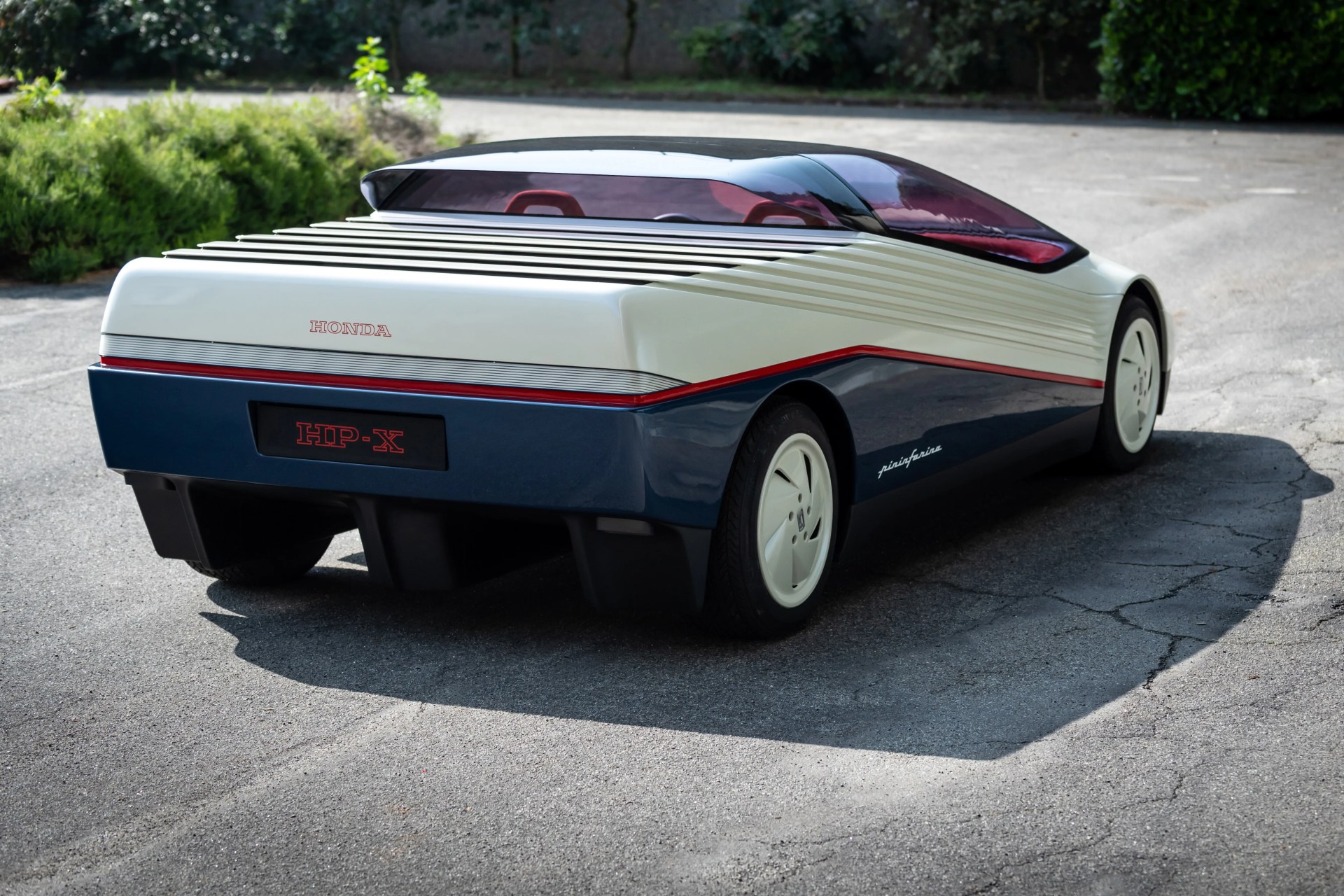 White and navy blue Honda HIP-X concept car with red accents and a sleek, futuristic design parked on pavement.