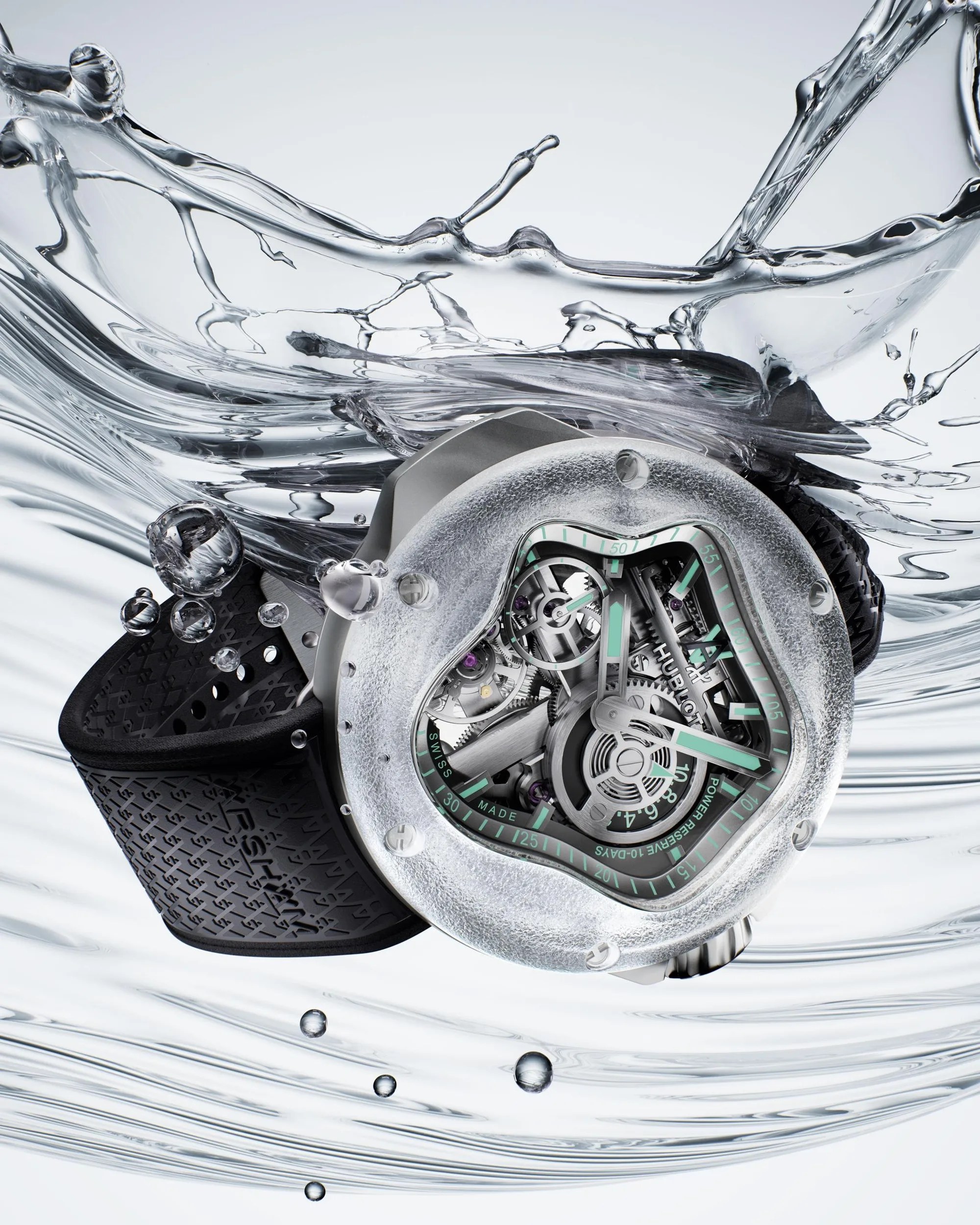 Silver mechanical wristwatch with a textured bezel and black rubber strap submerged in splashing water.