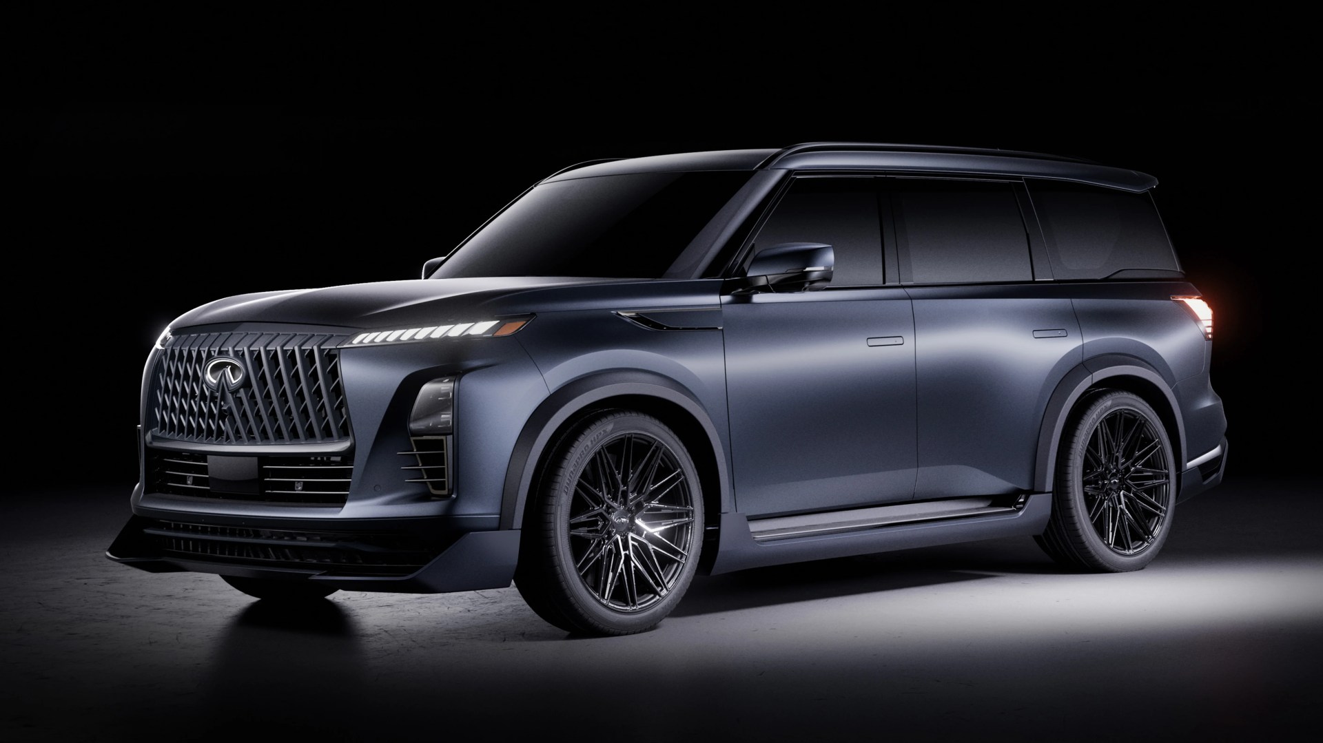 Matte dark blue Infiniti SUV with black multi-spoke wheels and tinted windows on a dark background.
