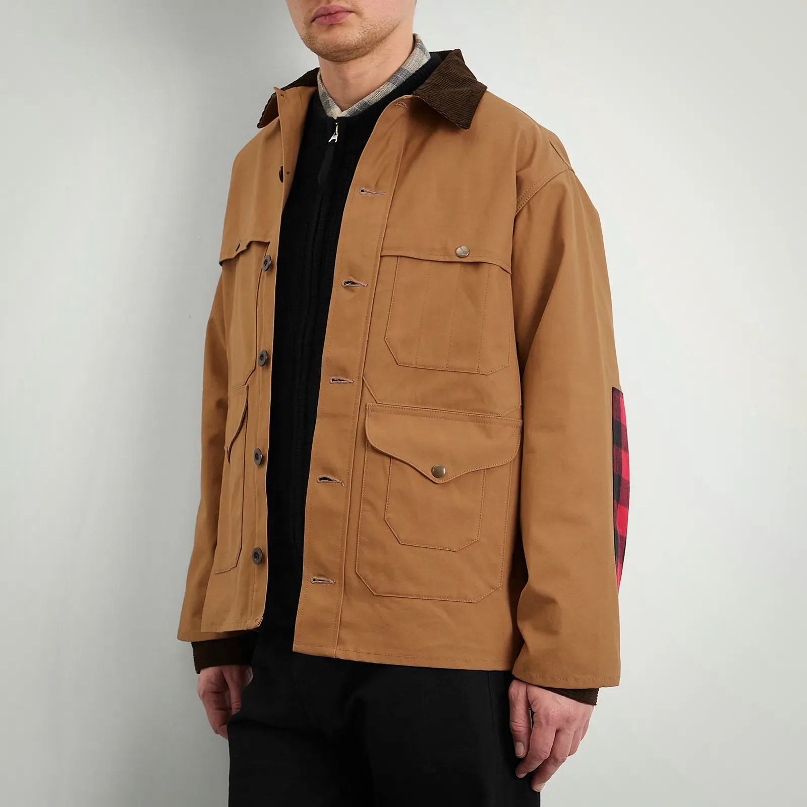 Brown button-up jacket with multiple front pockets and a dark brown collar worn over black pants.