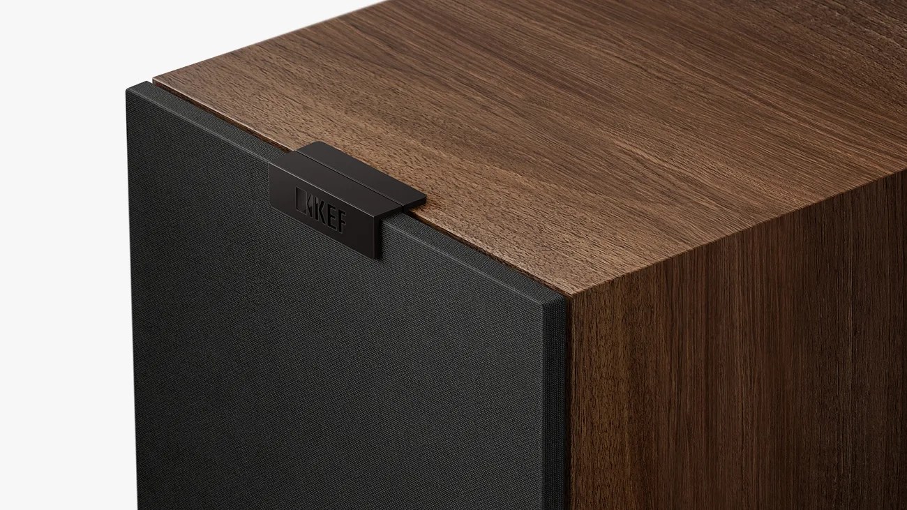 Close-up of a wooden speaker cabinet with a black fabric grille and a KEF logo badge on top.