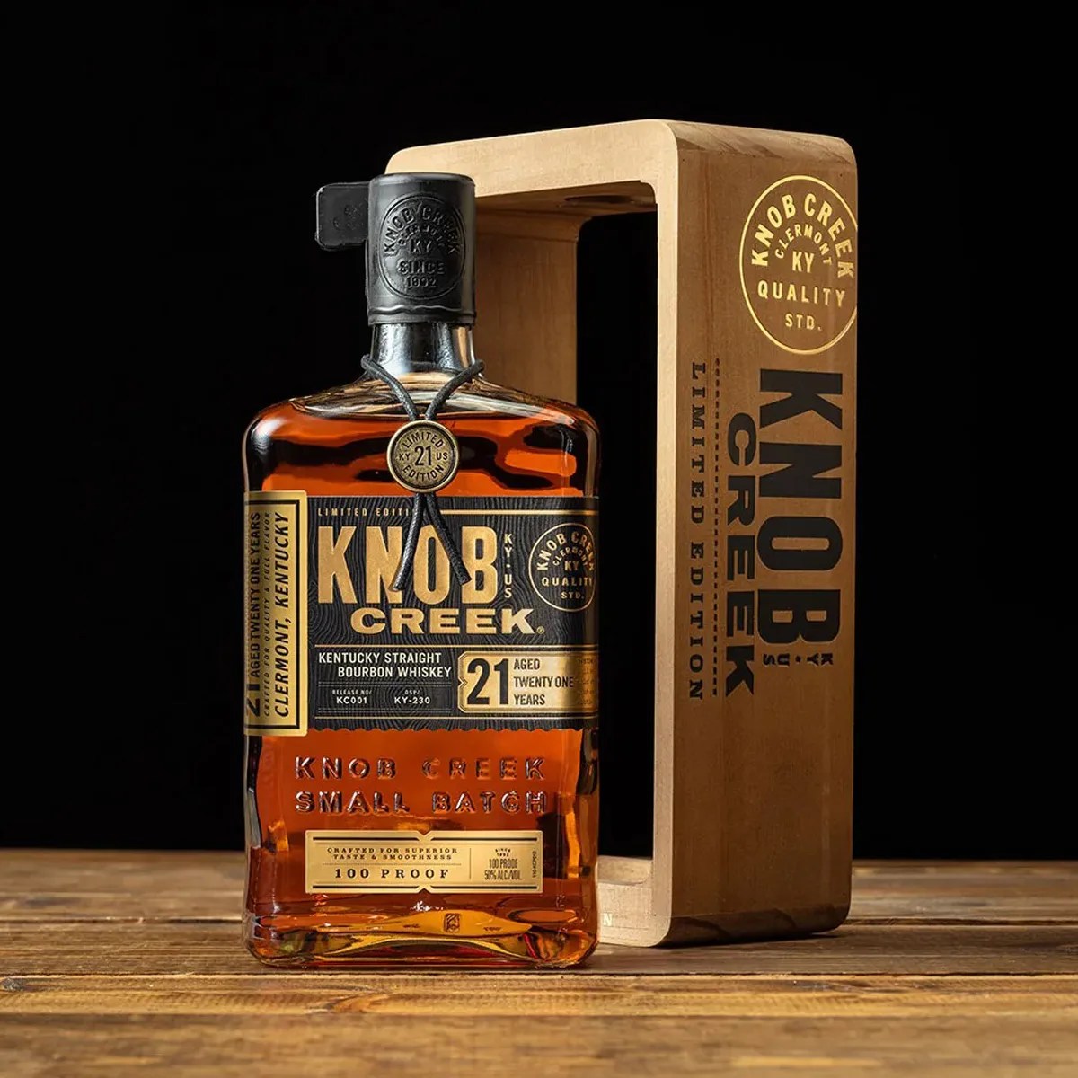 Bottle of Knob Creek 21-year-old Kentucky straight bourbon whiskey with wooden box on a wooden surface.