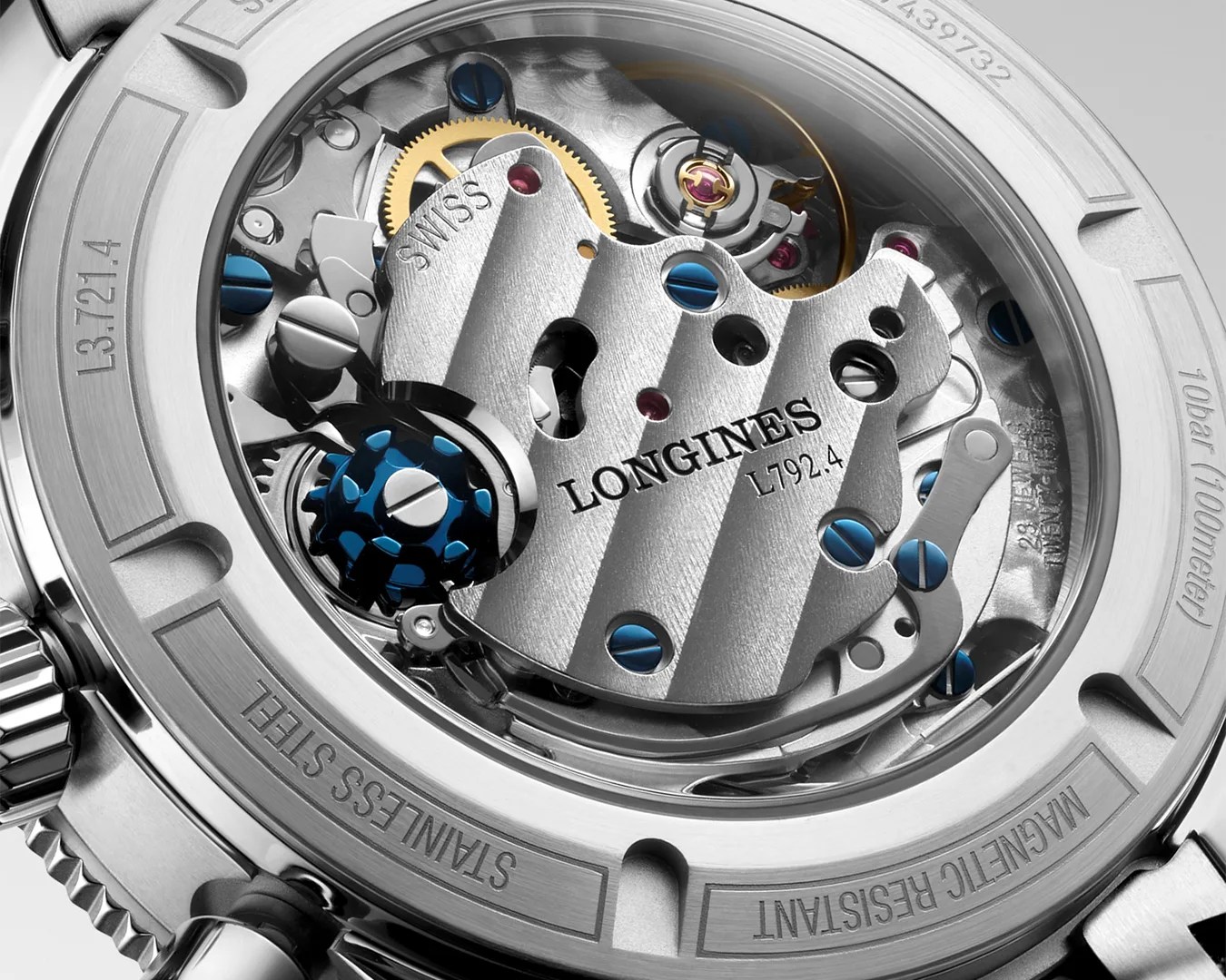 Close-up of a Longines watch movement with visible gears, blue screws, and stainless steel casing.