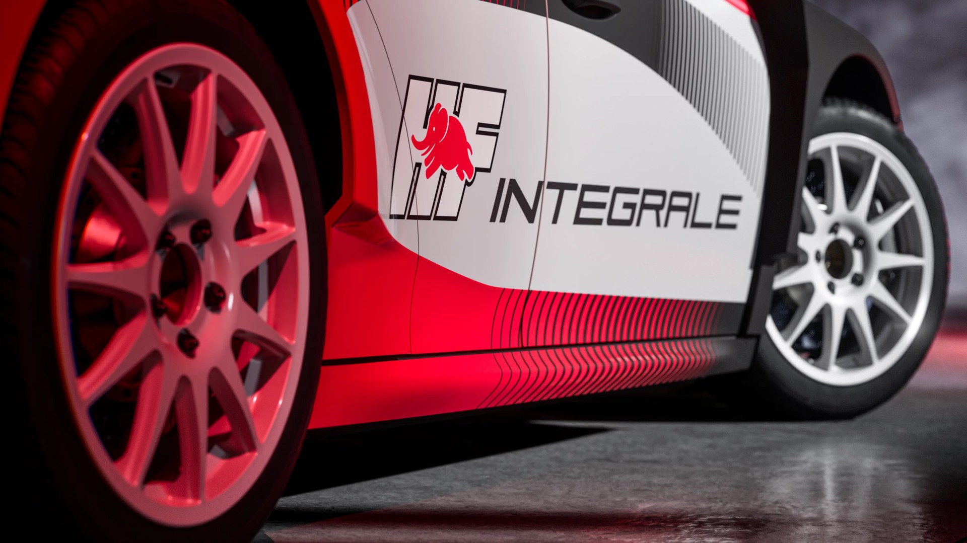 Close-up of white car side panel with "HF Integrale" logo and red elephant graphic, showing white multi-spoke wheels.